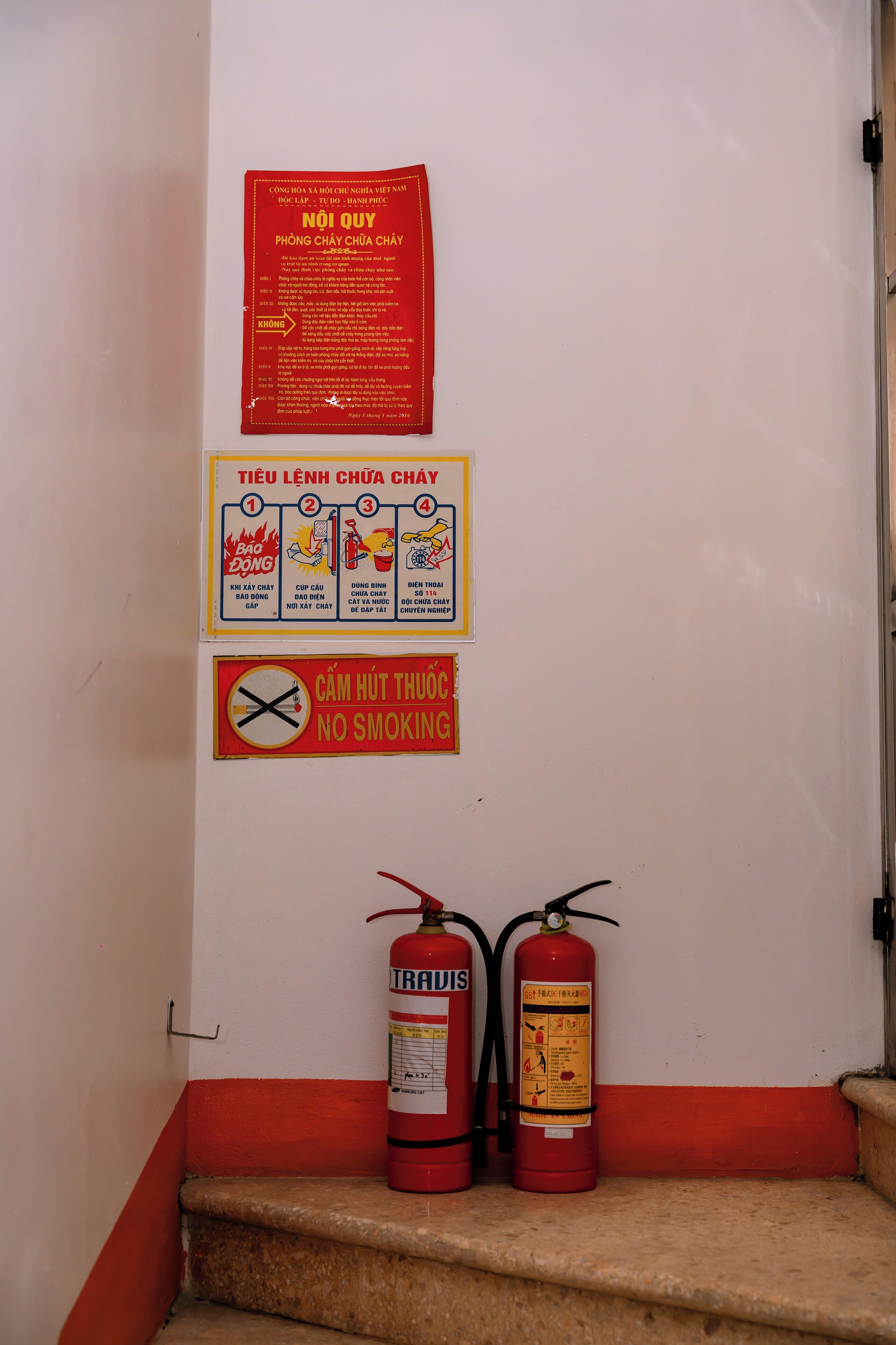 A staircase with fire extinguishers and safety signs on the wall.