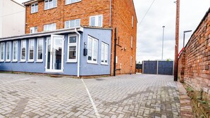 A paved courtyard with a blue building featuring large windows and a door. - Gloucester Kingsholm 6 Bedrooms (Gloucester)
