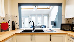 A kitchen with white cabinets, a black sink, and a microwave. - Gloucester Kingsholm 6 Bedrooms (Gloucester)