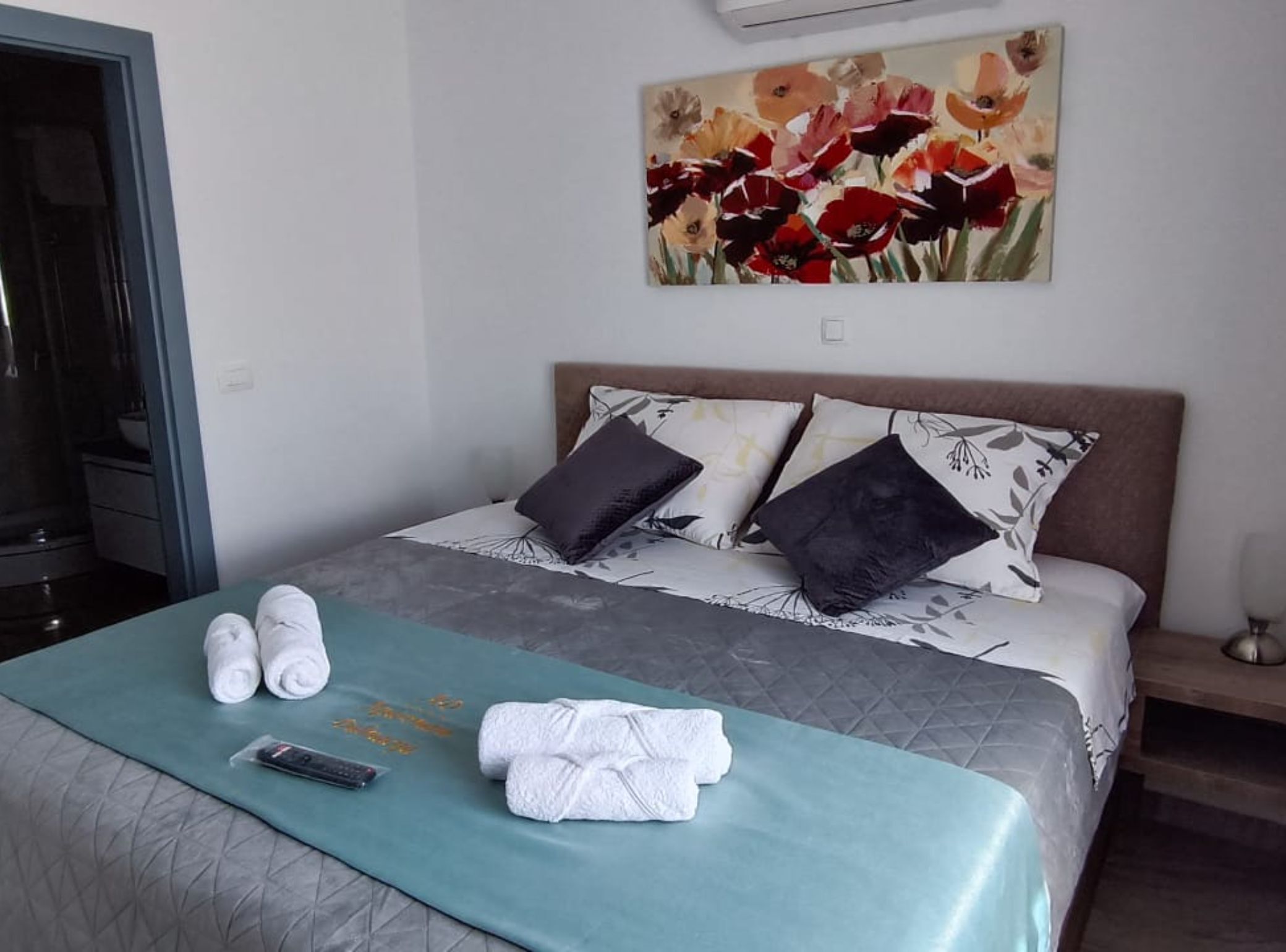Habitación de hotel con cama, almohadas, una colcha, toallas y un cuadro en la pared.