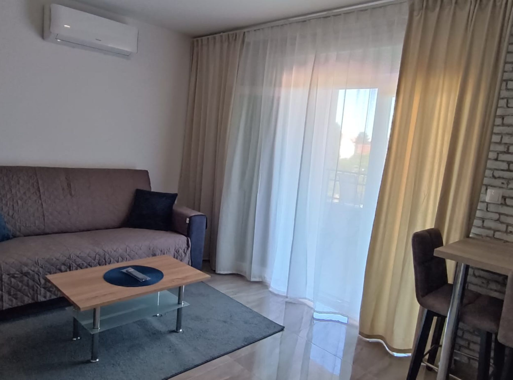 A modern living room with a sofa, a coffee table, and a dining area with a chair.