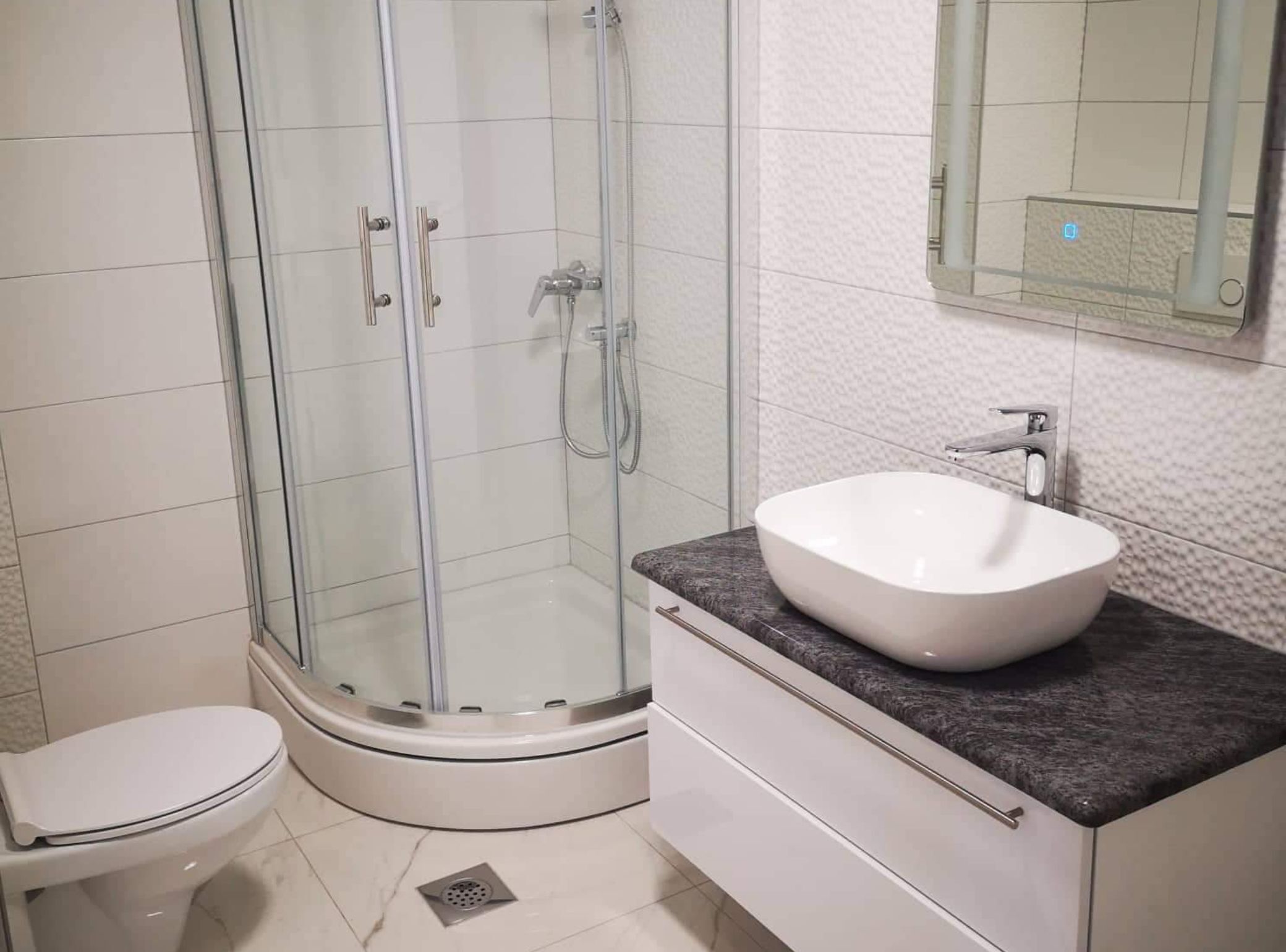 A modern bathroom with a glass-enclosed shower, a white sink, and a toilet.