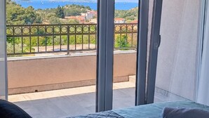 Une chambre avec un lit, une vue sur la côte et un balcon doté d’une balustrade.
