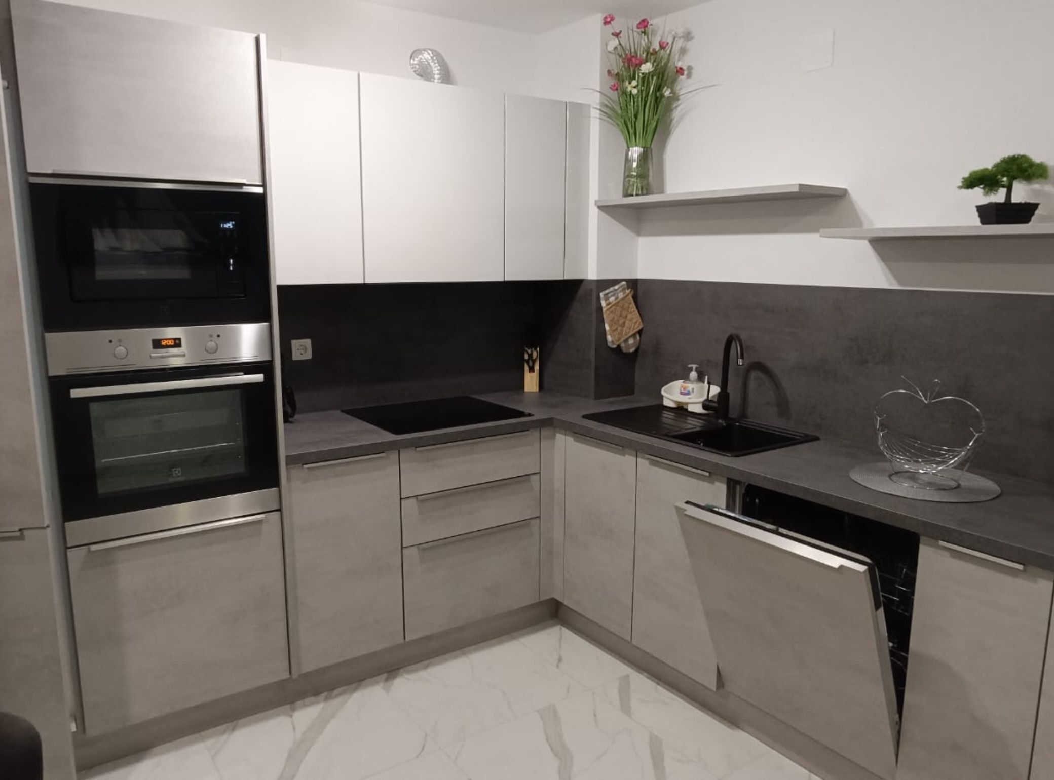 Una cocina moderna con electrodomésticos de acero inoxidable, encimera negra y diseño minimalista.