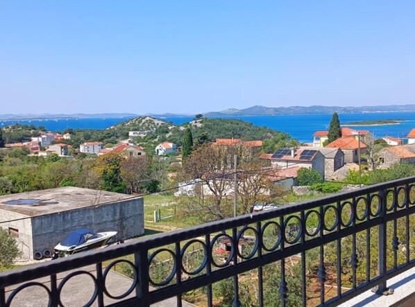 A coastal village with traditional houses, a clear blue sea, and a distant bridge. - Dalmatia Apartments (Pakostane)