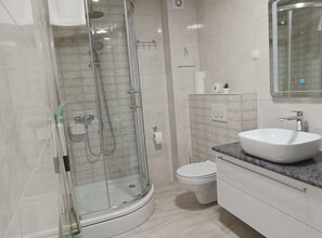 A modern bathroom with a glass-enclosed shower, a white sink, and a toilet. - Dalmatia Apartments (Pakostane)