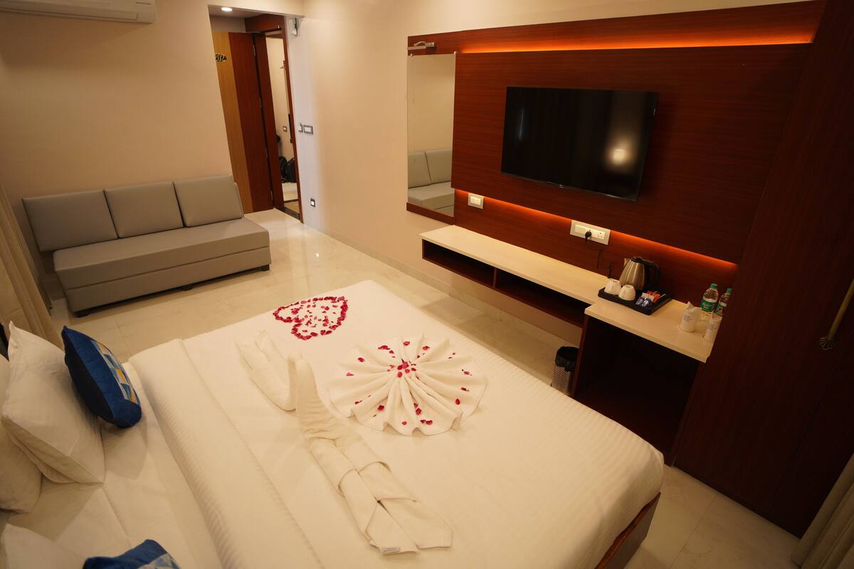 Una habitació d'hotel amb un llit, un sofà, una televisió i un mirall.