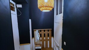 A narrow hallway with a wooden bench, a hanging lamp, and a mirror on the wall. - Big flat - Le Cala - City Center (Nice)