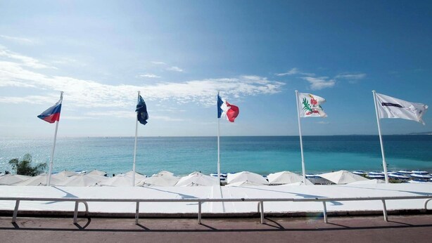A seaside promenade with flags, beach umbrellas, and a clear view of the ocean. - Big flat - Le Cala - City Center (Nice)