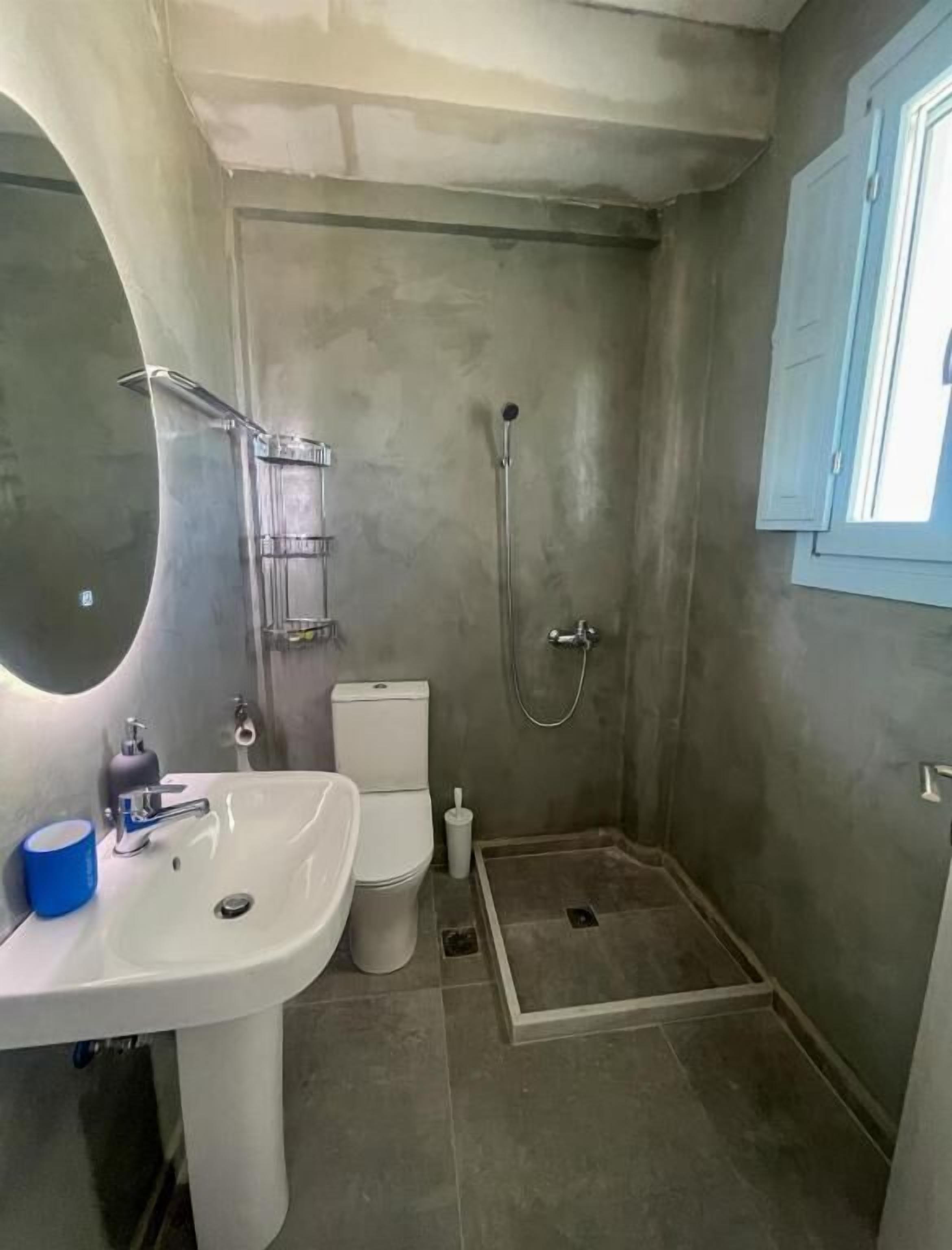 Un baño pequeño con lavamanos pedestal, inodoro y cabina de ducha.