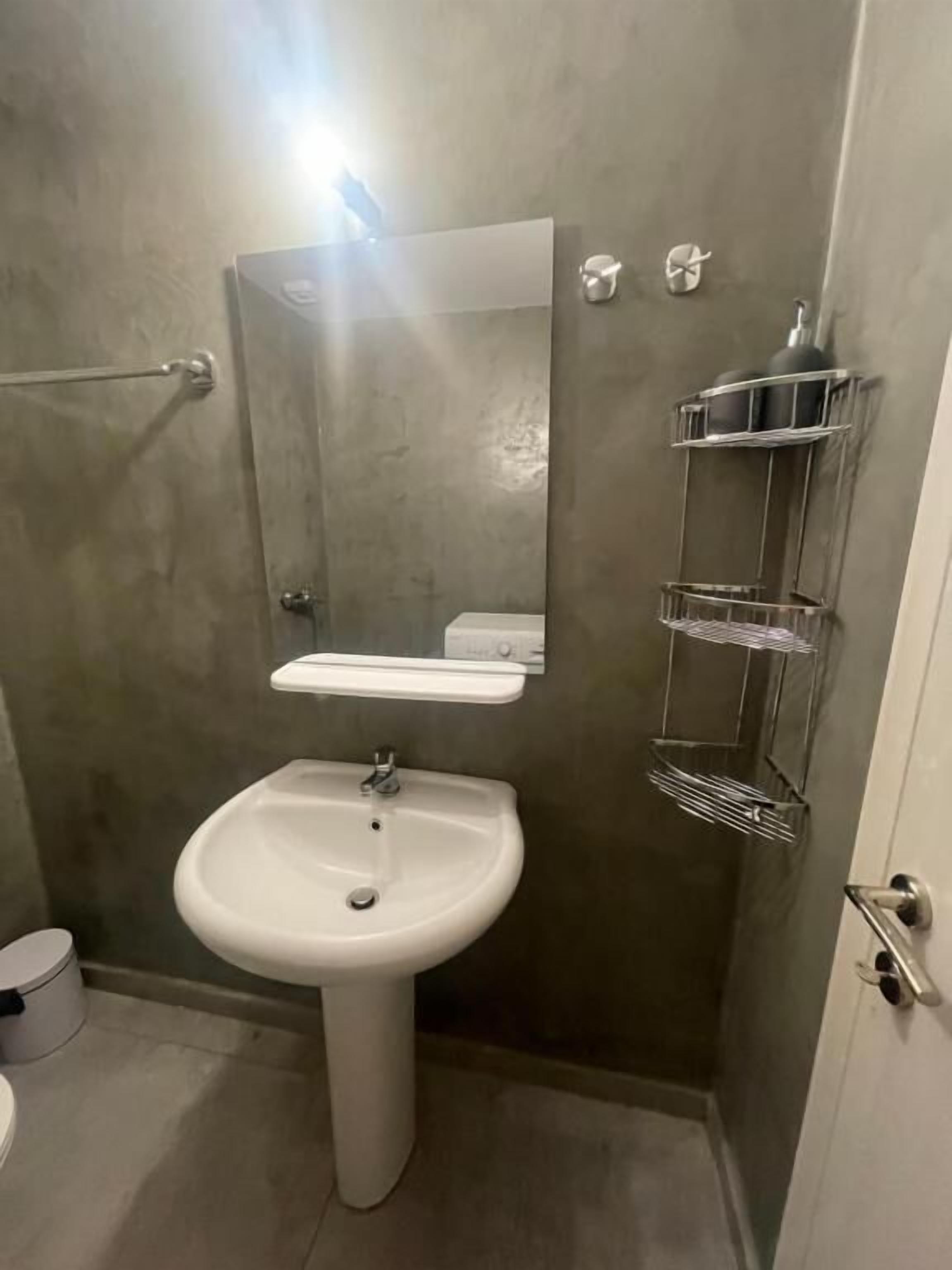A bathroom with a pedestal sink, a mirror, a towel rack, and a toilet.