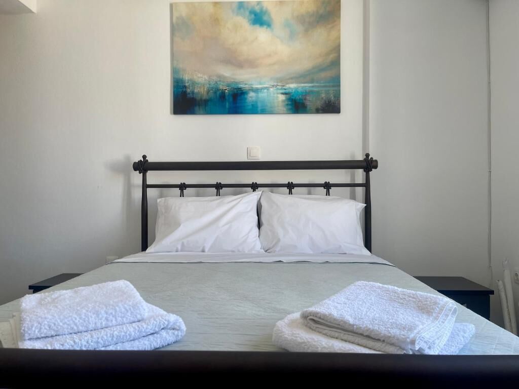 Una cama bien hecha con sábanas blancas y dos toallas dobladas a un lado.