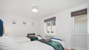 Un dormitorio moderno con dos camas, una ventana con vistas y decoración en la pared.