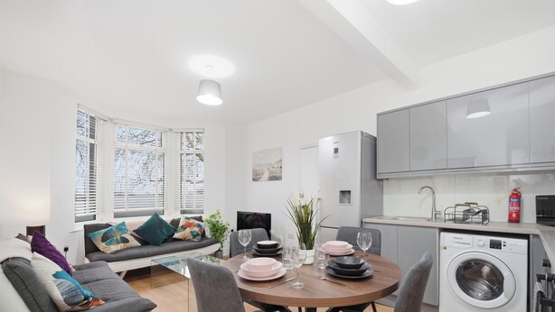 Un apartamento moderno con comedor, sofá, cocina e instalaciones de lavandería.