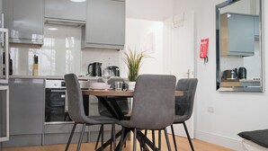 Una cocina moderna con armarios grises, una mesa de comedor con dos sillas, una cafetera y una planta en maceta.