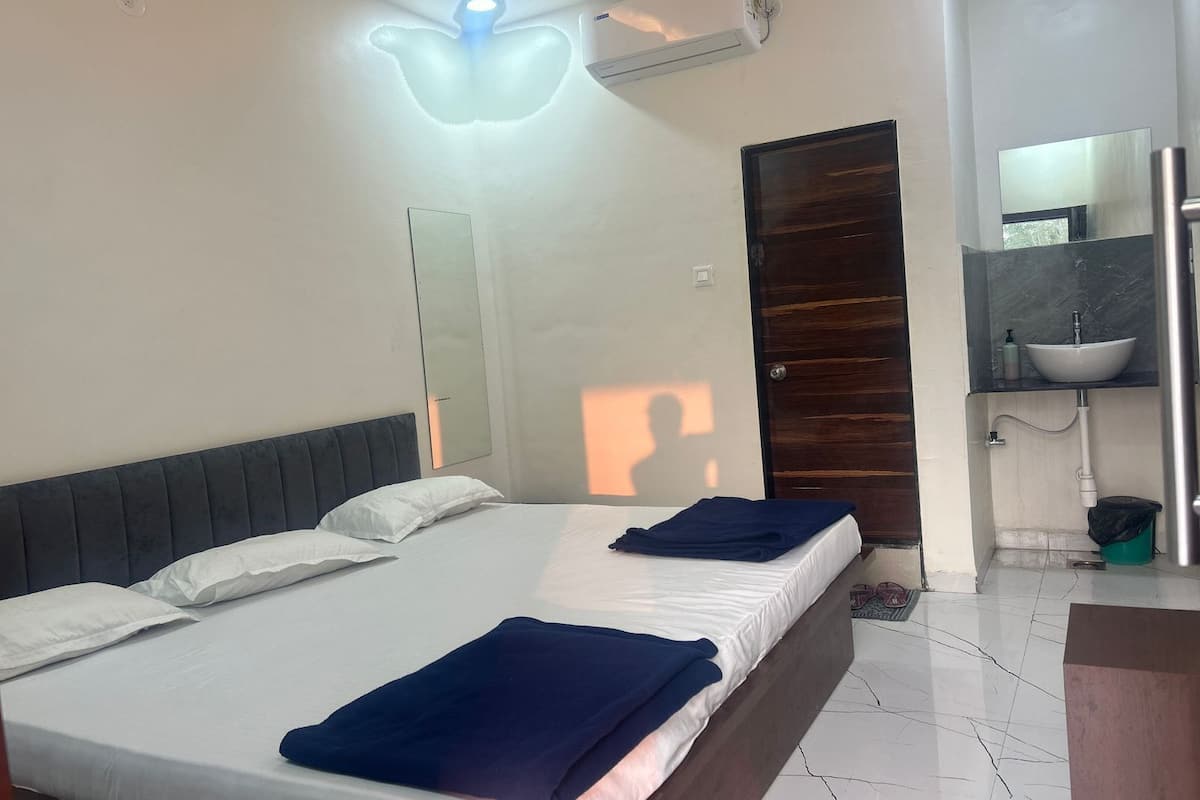 Une chambre d’hôtel équipée d’un lit, d’un miroir, d’une salle de bain avec un lavabo et d’un appareil de climatisation.