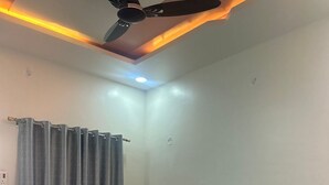 A bedroom with a bed, two pillows, a headboard, a ceiling fan, and a window with curtains. - MORESHWAR PRIDE & RESIDENCY (Khuldabad)
