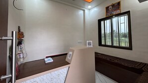 A room with a desk, a window with bars, a ceiling fan, and a wall-mounted QR code. - MORESHWAR PRIDE & RESIDENCY (Khuldabad)