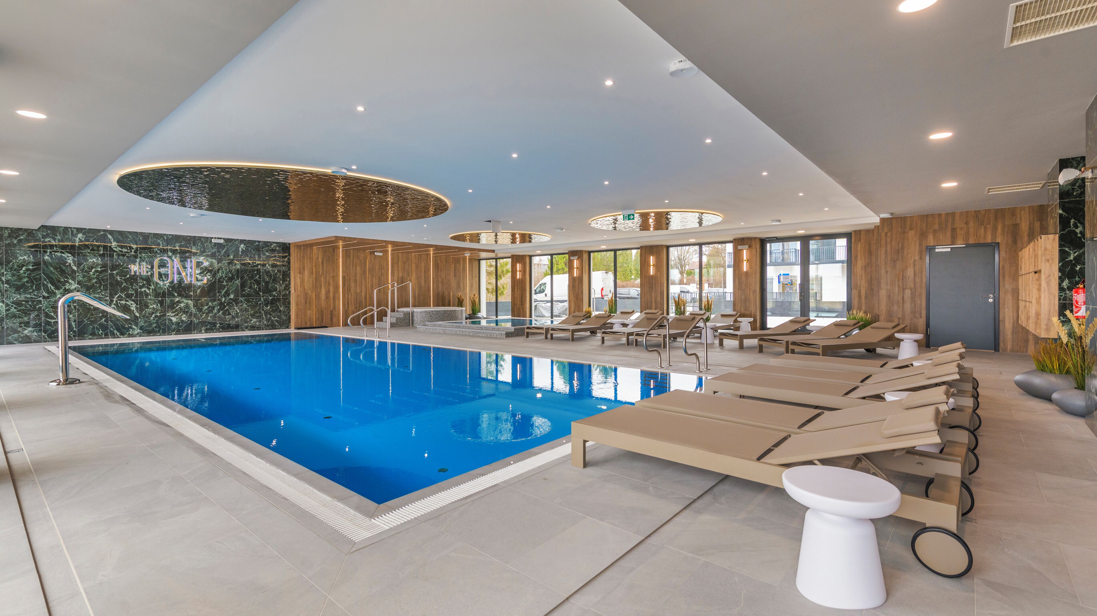An indoor swimming pool with lounge chairs and a white toilet.