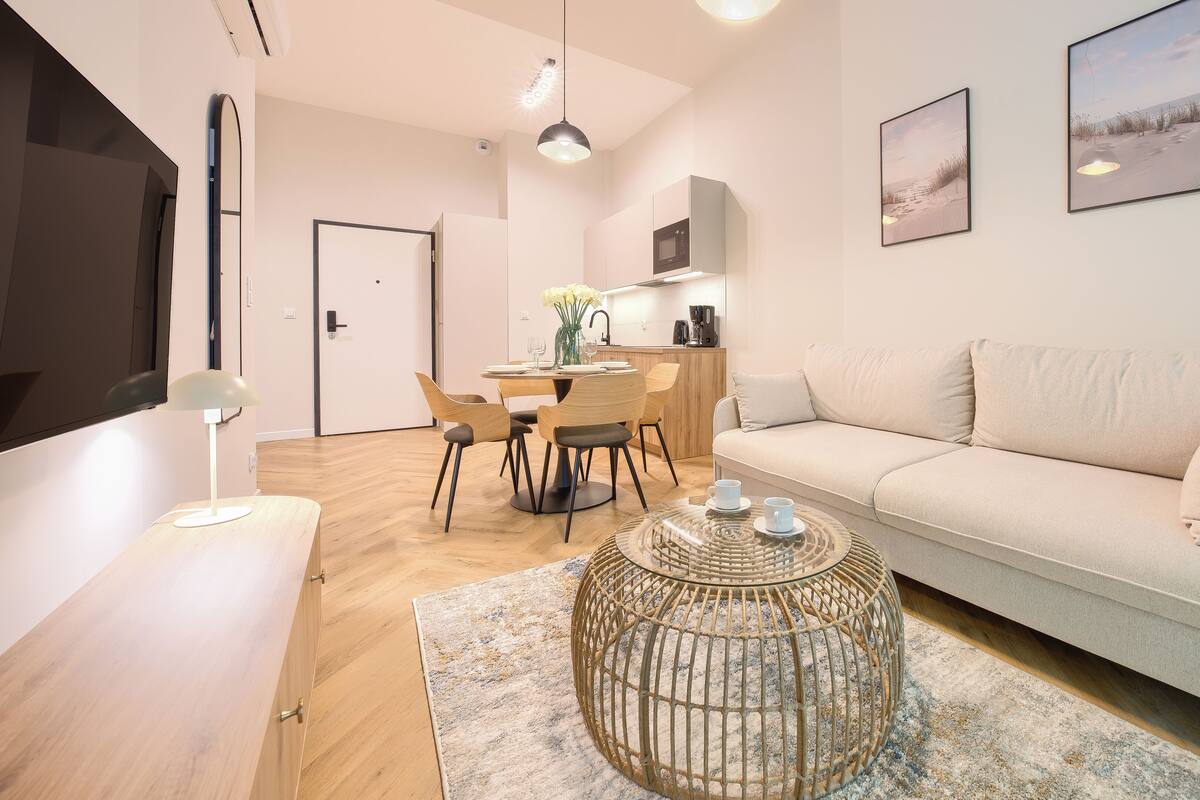 Ein modernes Wohnzimmer mit Sofa, Couchtisch, Essbereich und Küche.