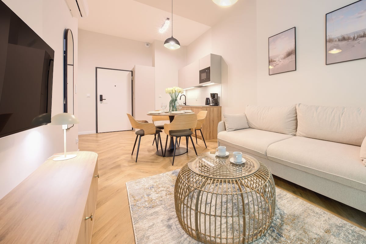 Una sala moderna con sofá, mesa de centro, comedor y cocina.