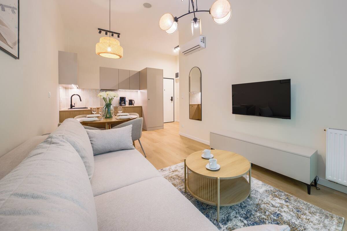 Ein modernes Wohnzimmer mit einer Couch, einem Couchtisch und einem an der Wand befestigten Fernseher.
