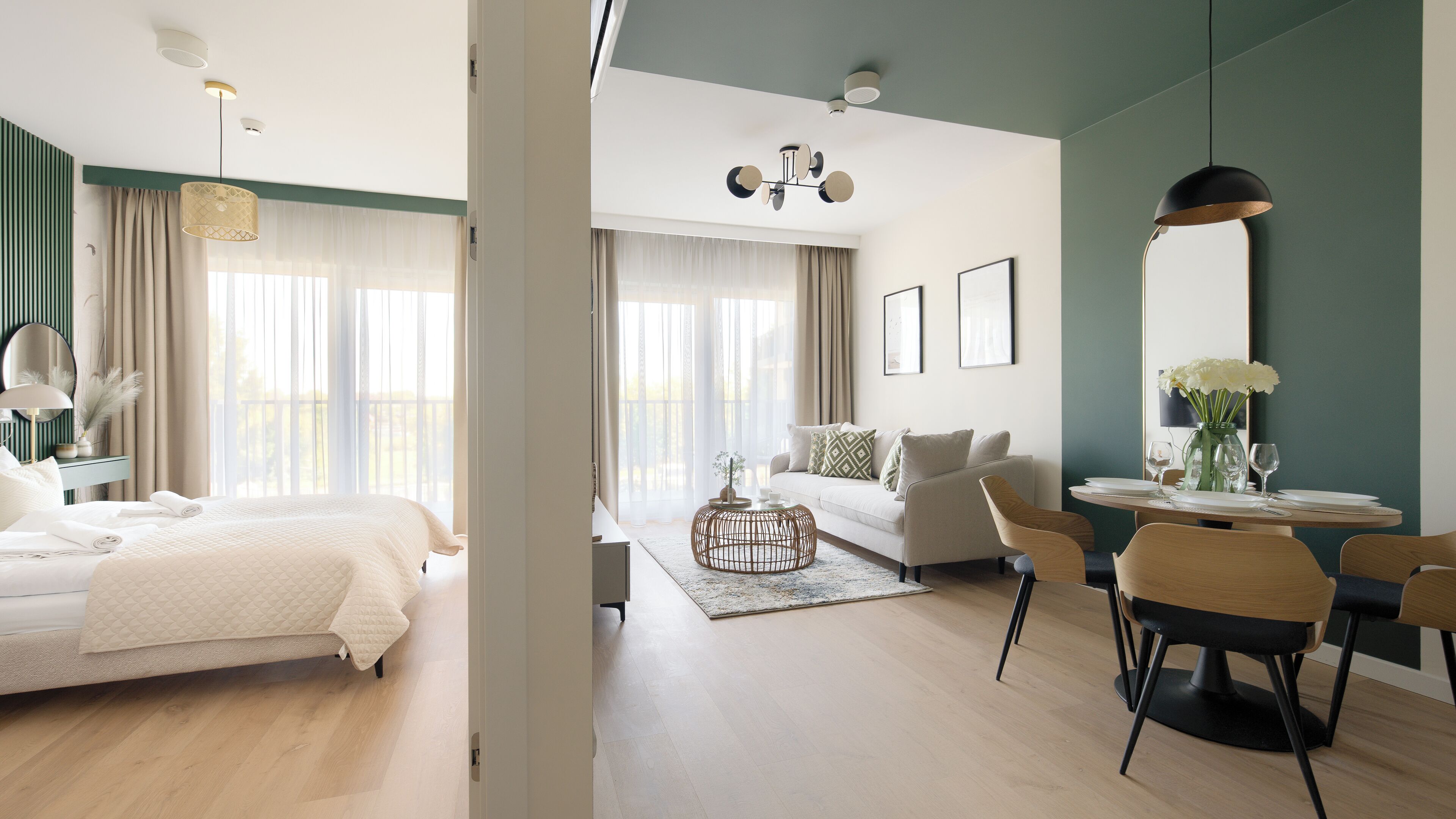 Una habitación de hotel moderna con cama, sofá, zona de comedor con sillas y un gran ventanal.
