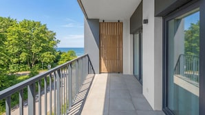 A balcony with a view of the sea, a wooden door, and a glass wall. - Apartamenty Sun & Snow The One Ustronie Morskie (Sianożęty)