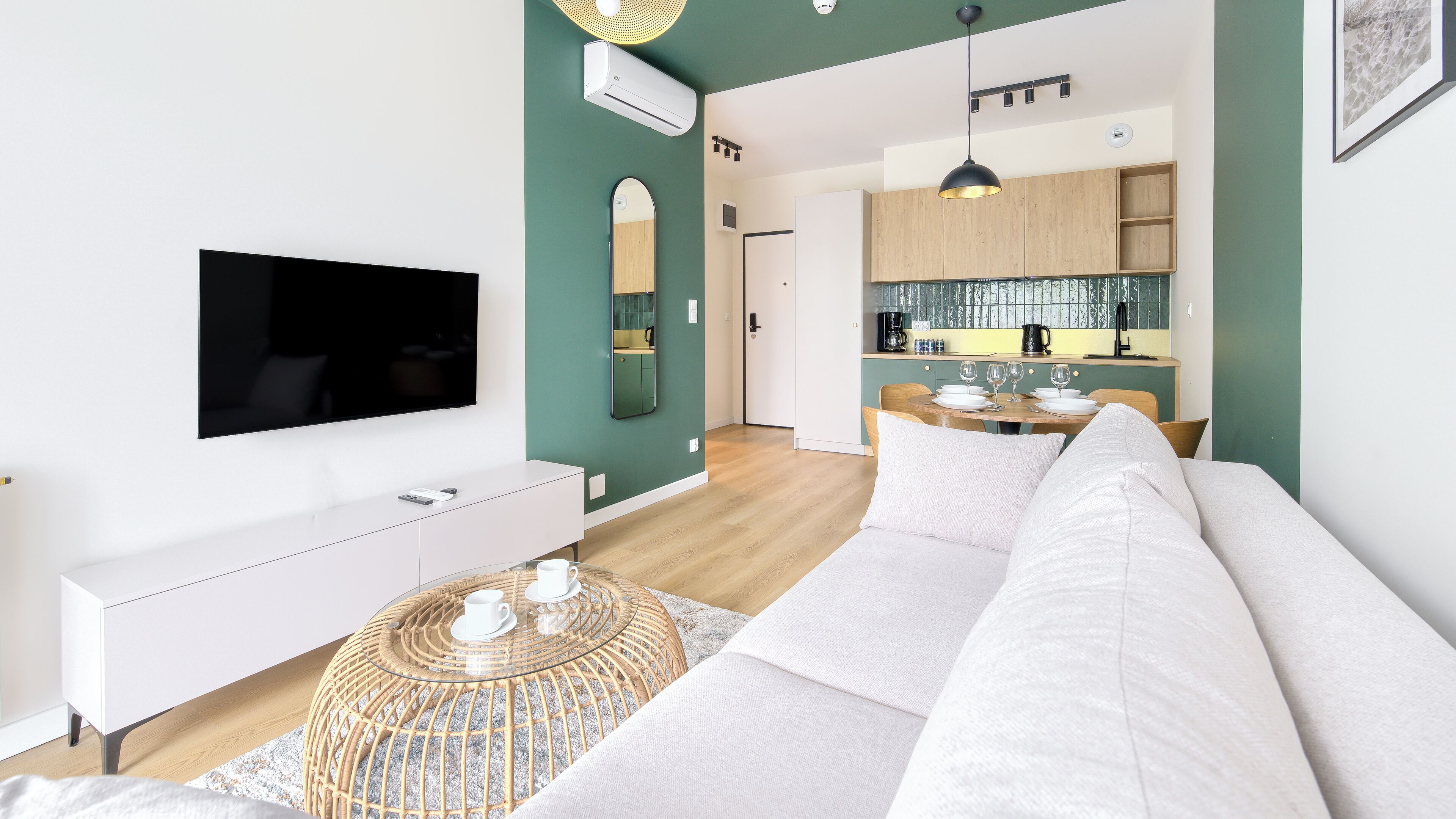 Una sala de estar moderna con un televisor de pantalla plana, un sofá blanco y una mesa de centro de vidrio.