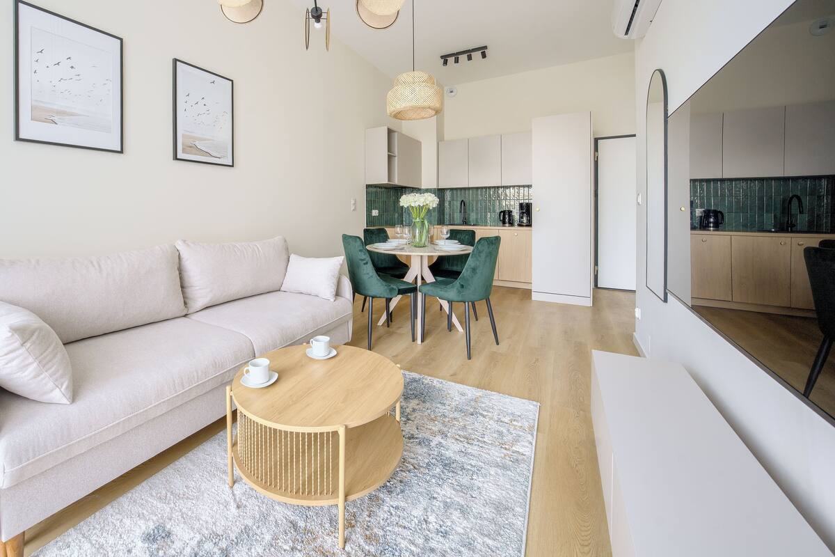 Ein modernes Wohnzimmer mit einer Couch, einem runden Couchtisch und einem Essbereich mit Stühlen und einem Tisch.
