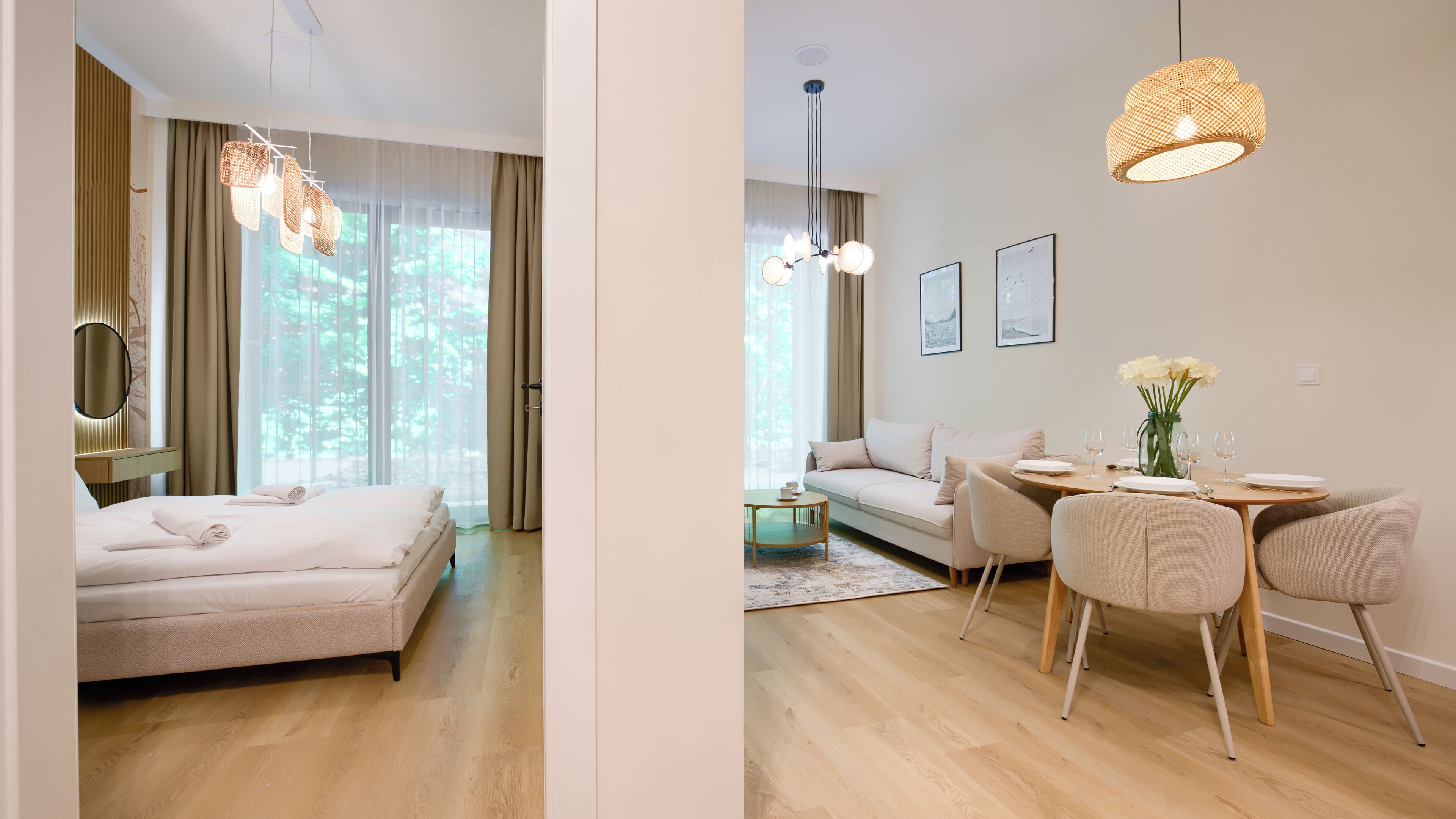 Habitación de hotel con cama, zona de estar con sofá, mesa de comedor con sillas y un ventanal con cortinas.