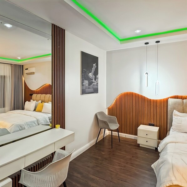 A modern bedroom with a bed, bedside table, chair, and a desk. - Breics Extended Stay (Abuja)