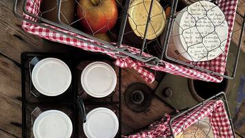 A wooden table with baskets containing bread, apples, cheese, and jars.