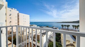 Un balcone con vista sul mare, edifici e palme.