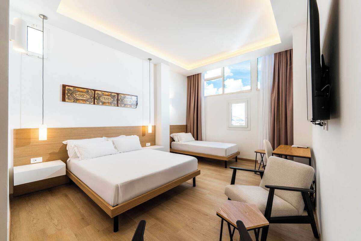 Ein Hotelzimmer mit zwei Betten, einem Schreibtisch, einem Stuhl und einem Fernseher.