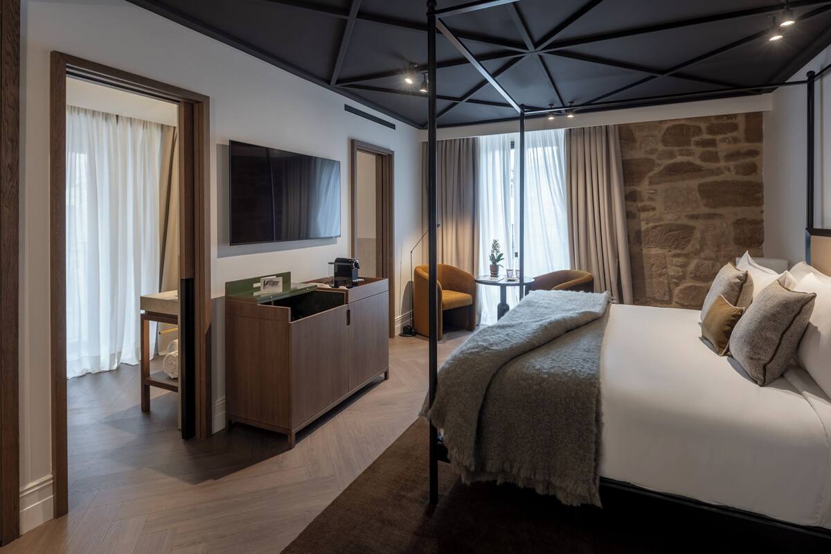 Una habitación de hotel moderna con una cama grande, un escritorio, una silla y una pared de acento de piedra.