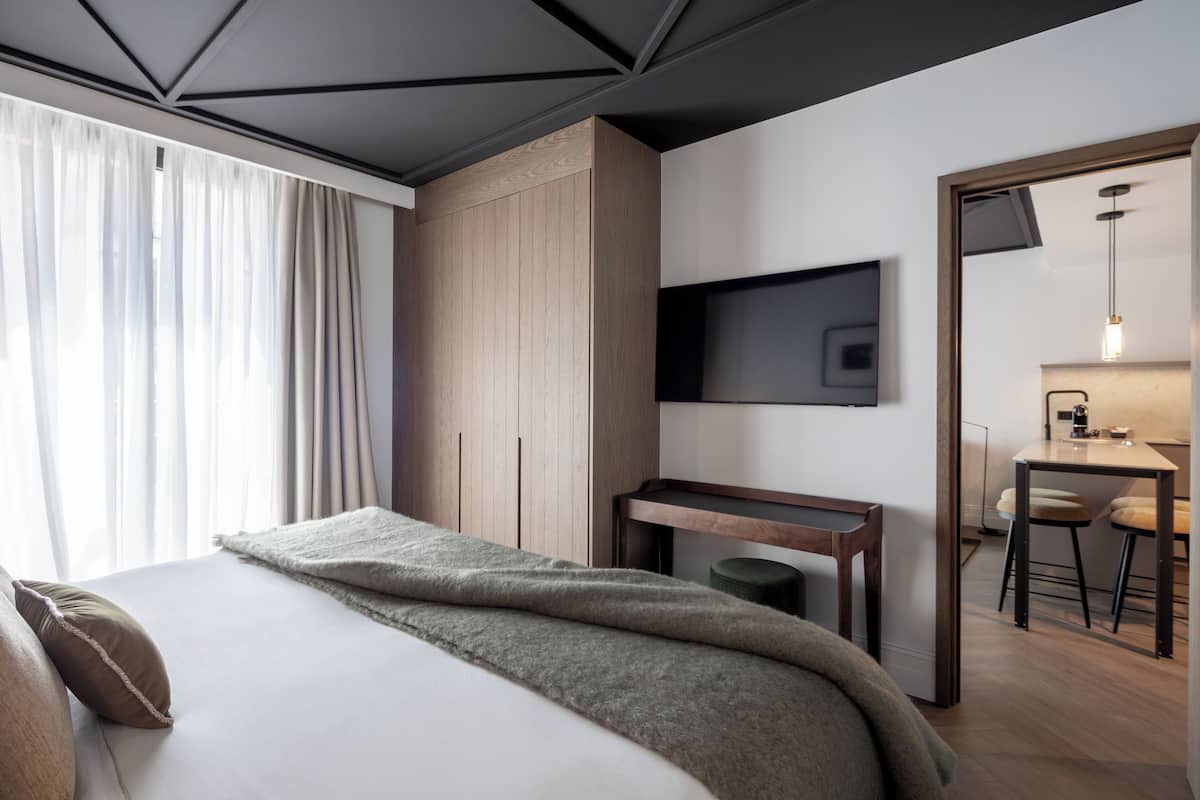 Una habitación de hotel moderna con cama, escritorio, televisor y zona de comedor.