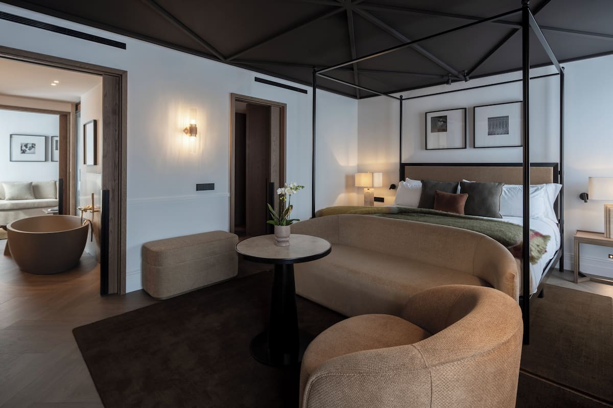 Un dormitorio moderno con una cama con dosel, una mesita redonda y un sofá.