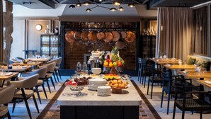 A restaurant with a long communal table, chairs, and a buffet with various food items.