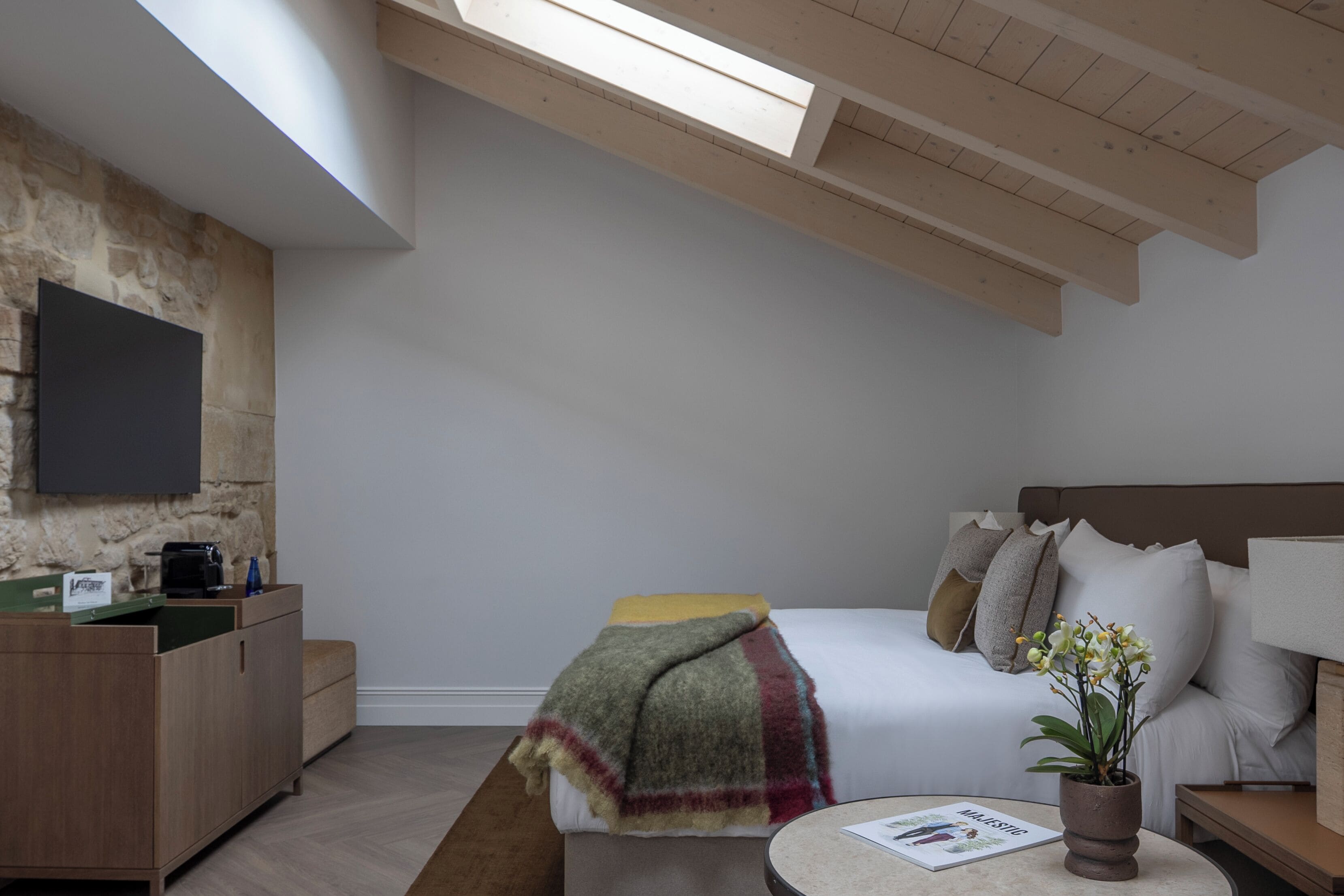 Un dormitorio con cama, mesita de noche, lámpara y planta en maceta.