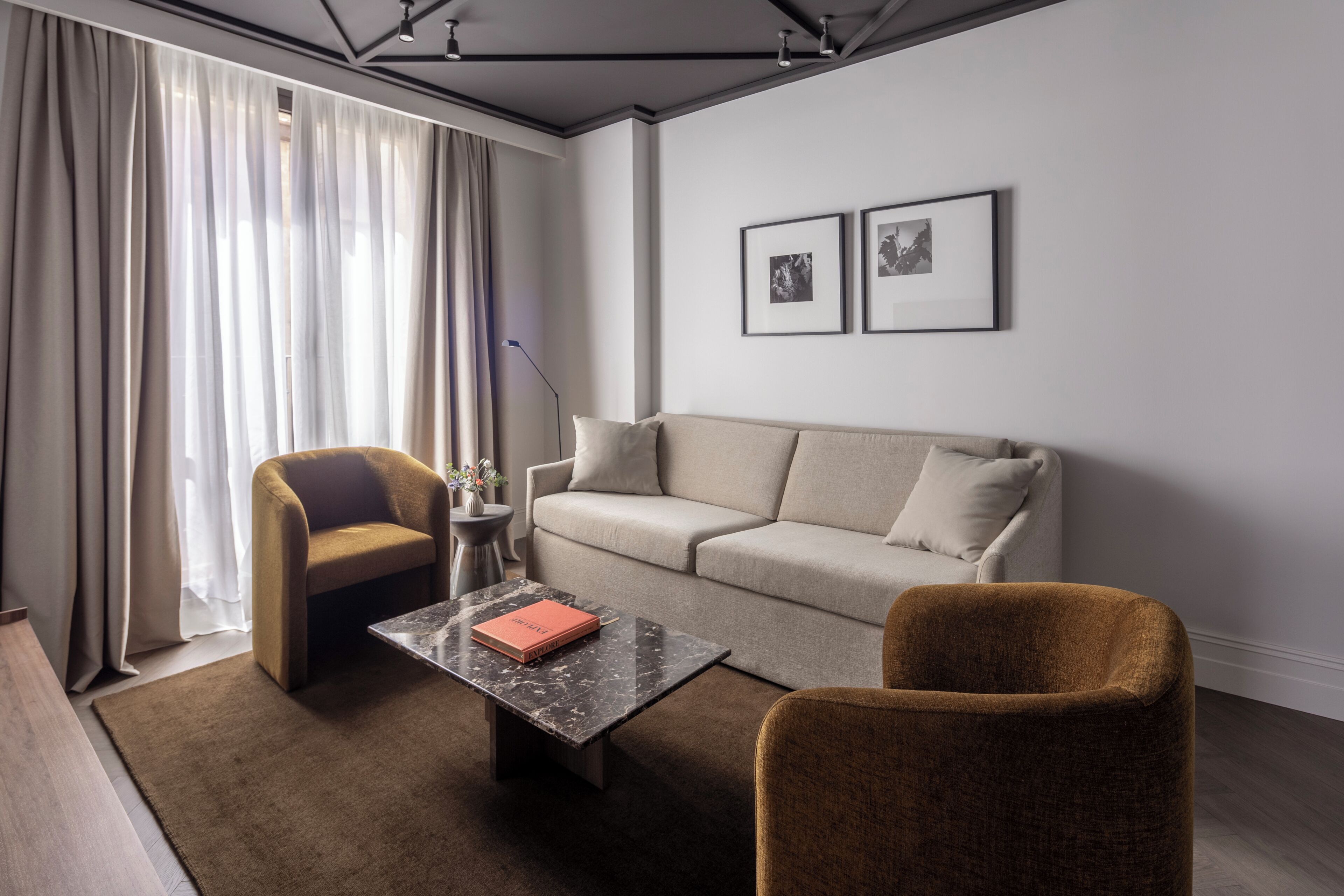 Una sala de estar moderna con un sofá, dos sillones, una mesita de centro y una lámpara de pie.