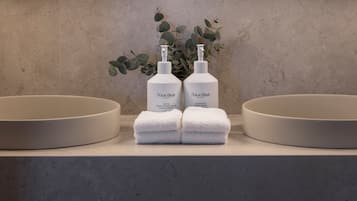 Un tocador de baño con dos lavamanos, un espejo y dos botellas de productos para el cuidado de manos Natura Bisse.
