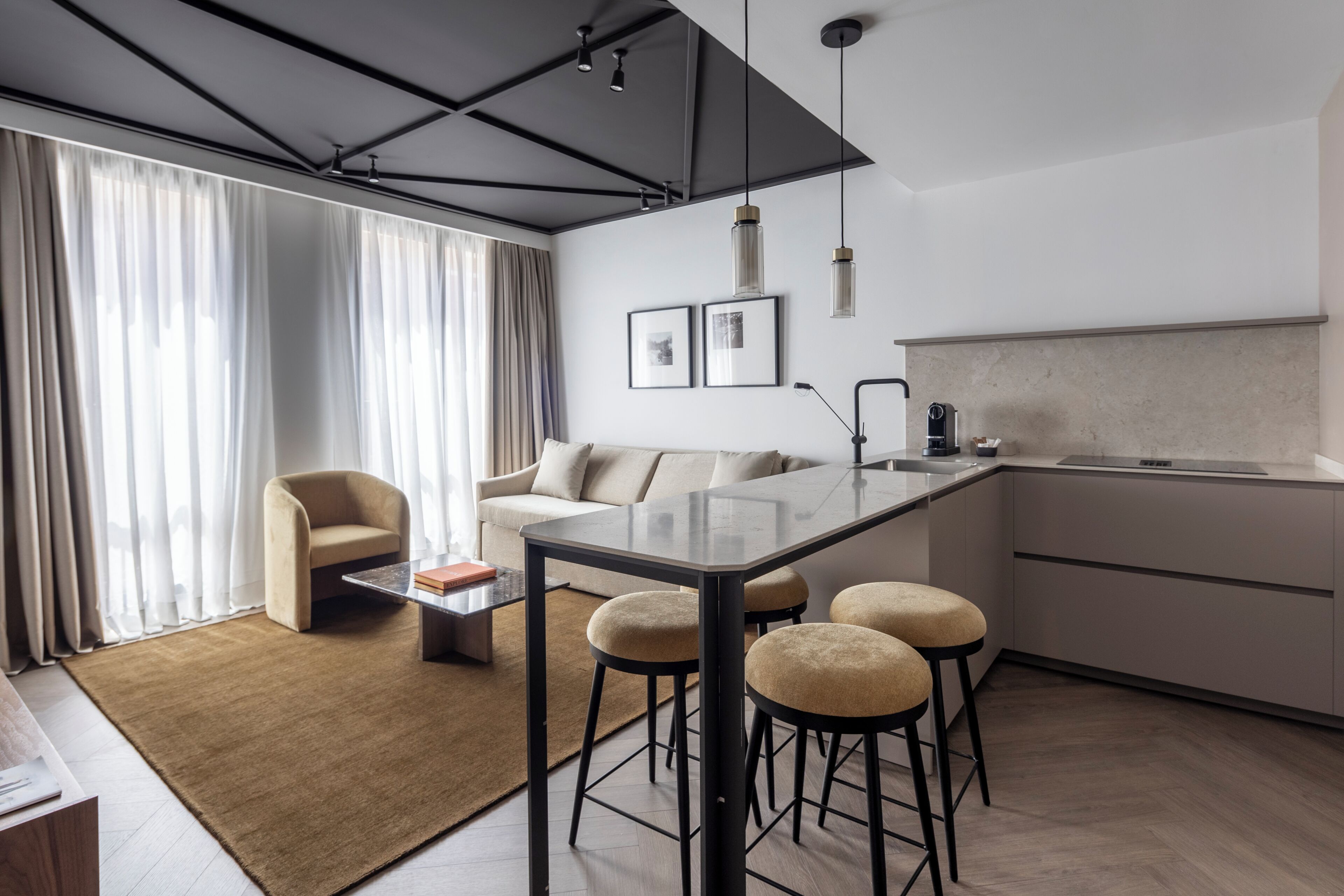 Una cocina moderna con barra, una mesa de comedor con taburetes, un sofá y una mesa de centro.