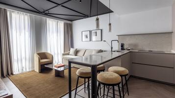 Una cocina moderna con barra, una mesa de comedor con taburetes, un sofá y una mesa de centro.