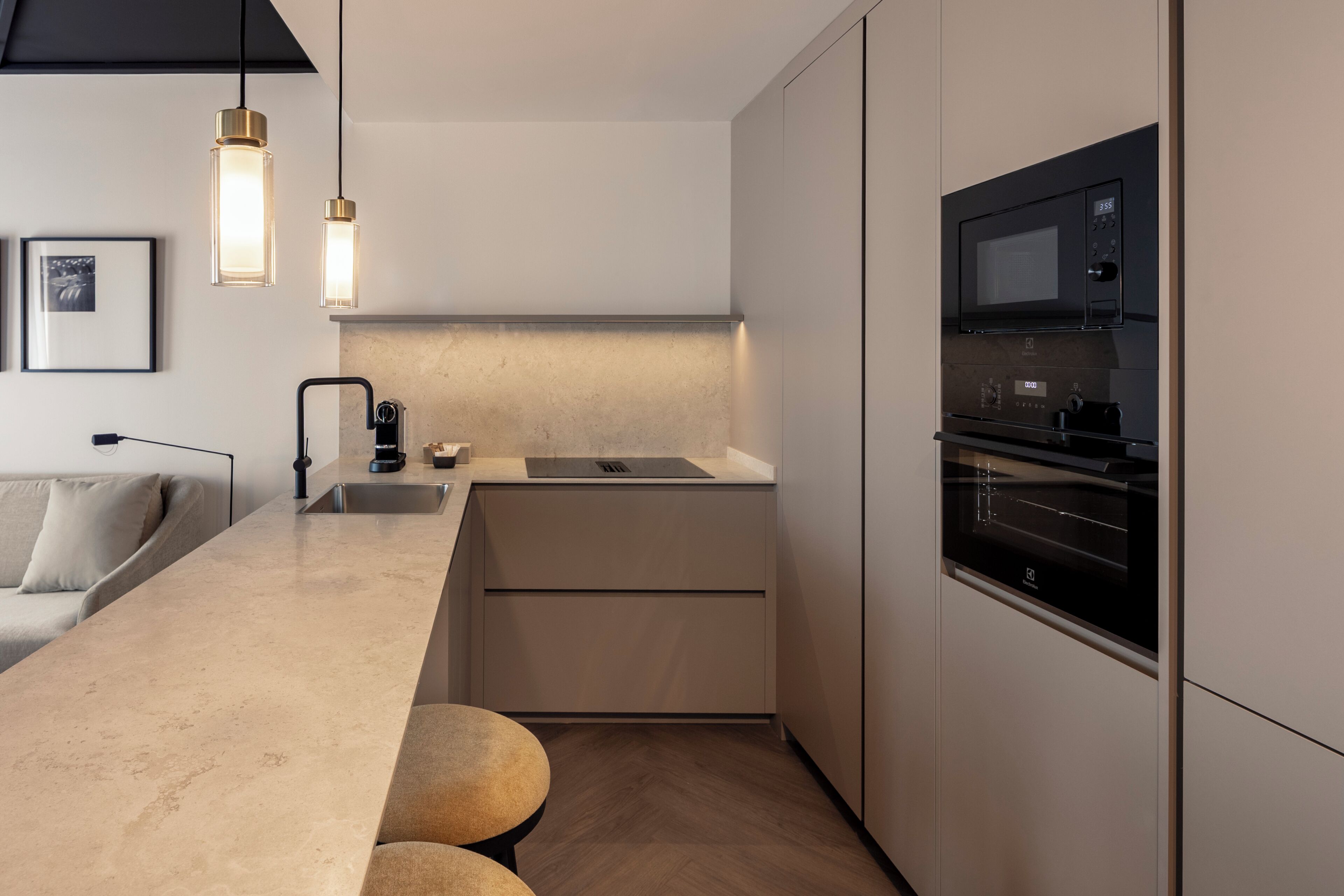 Una cocina moderna con horno empotrado, lavamanos e iluminación colgante.