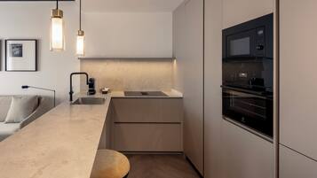 Una cocina moderna con horno empotrado, lavamanos e iluminación colgante.