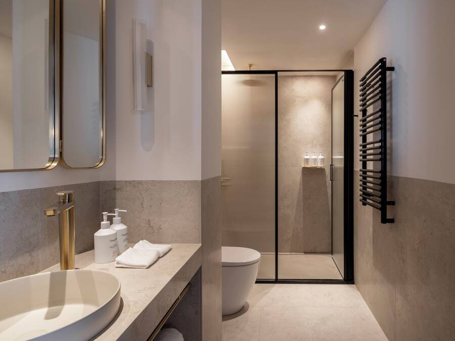 Un baño moderno con un lavamanos grande, un inodoro, una cabina de ducha de vidrio y un perchero para toallas.