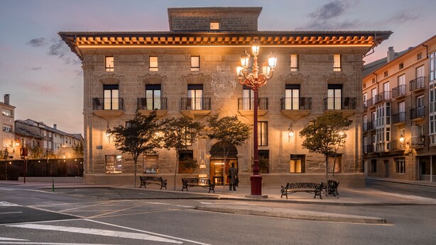 A historic building with a central entrance, multiple balconies, and a decorative chandelier.