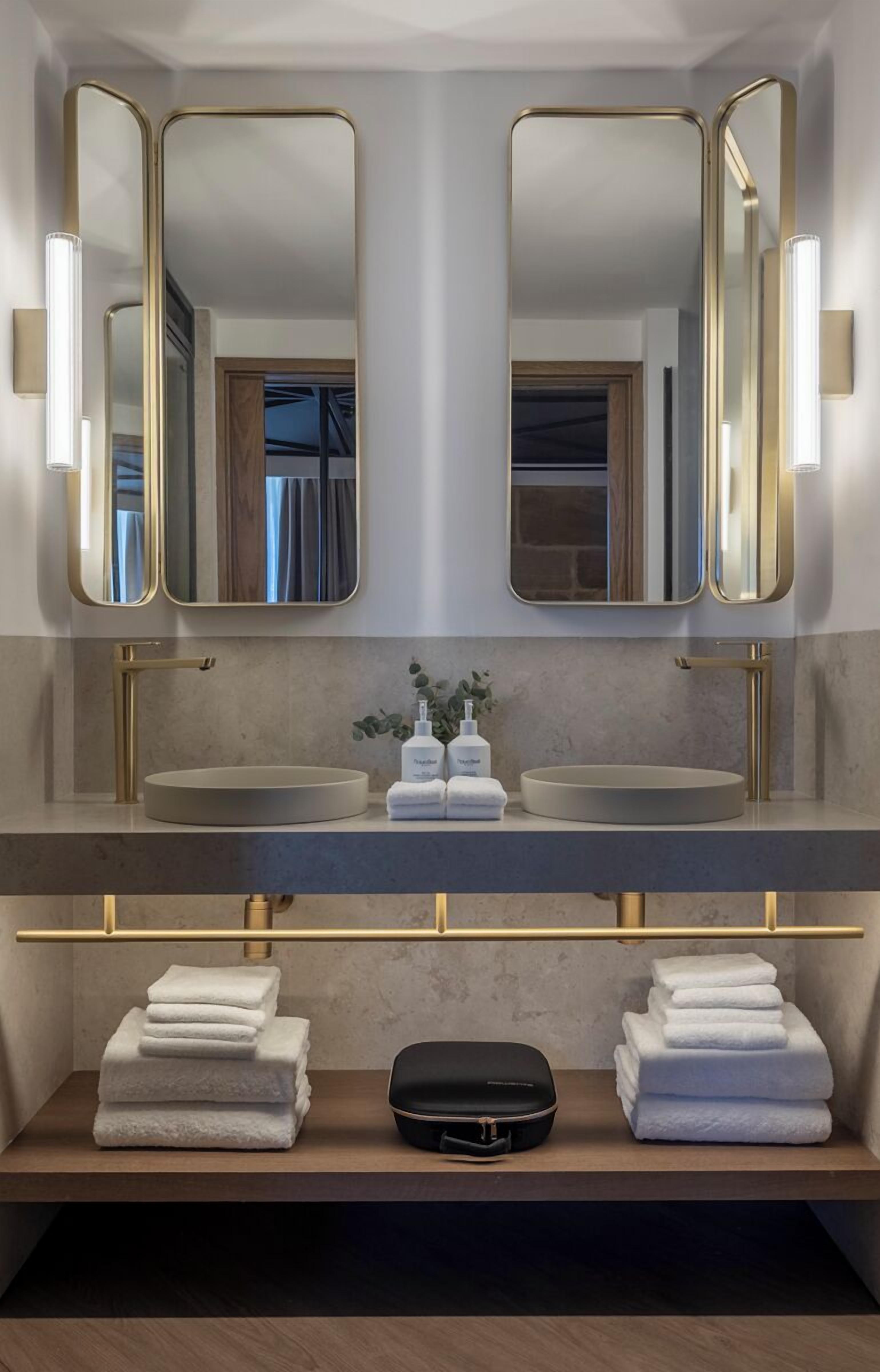 Un baño moderno con lavamanos doble, dos espejos y un perchero para toallas.