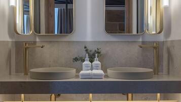 Un baño moderno con lavamanos doble, dos espejos y un perchero para toallas.